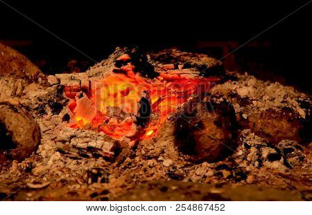 Burning Coals In The Fireplace On A Blurred Background, The Texture Of The Flame
