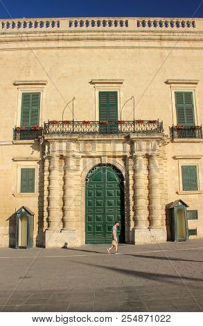 Valletta, Malta - May 2018: Man Walk In Valletta Along Close Big Green Gate Of Grandmaster Palace In