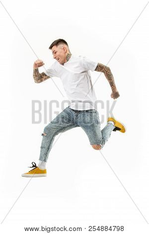 Freedom In Moving. Mid-air Shot Of Handsome Happy Young Man Jumping And Gesturing Against White Stud