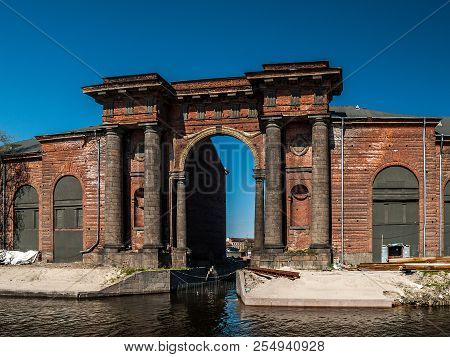 The Architectural Structure Of The Arch Of Red Brick With Columns, Niches, Portico Rises On The Isla