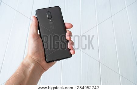 Khakiv, Ukraine - 14 August 2018: Modern Smartphone OnePlus 6 in a hand on the white wooden background