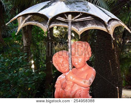 Sculpture Of Boy And Girl With Umbrella In The Garden Of Alameda Apodaca In Cadiz Capital, Andalusia