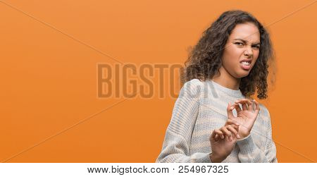 Beautiful young hispanic woman wearing stripes sweater disgusted expression, displeased and fearful doing disgust face because aversion reaction. With hands raised. Annoying concept.