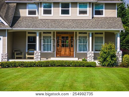 Entrance Door Of Residential House  With Dressed Green Lawn On The Front Yard.