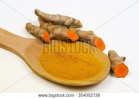 Turmeric Powder In A Wooden Spoon And Fresh Turmeric Roots Isolated On A White Background Is An Ingr
