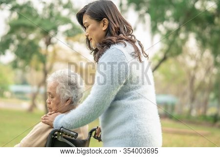 Help And Care Asian Senior Or Elderly Old Lady Woman Patient Sitting On Wheelchair At Park In Nursin