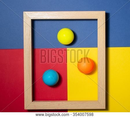 Wooden Frame With Colored Balls Inside, On A Multi Colored Background. Space For Copy-paste. Top Vie