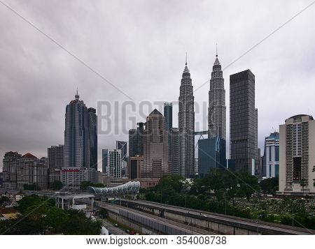 A View Of The Kuala Lumpur Skyline With Cloudy Weather. The Skyline Is Dotted With Tall Skyscrappers