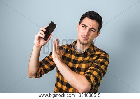 Handsome Man In Yellow Shirt Annoyed By Someones Voice On Phone Gesturing With His Hand Saying No Mo