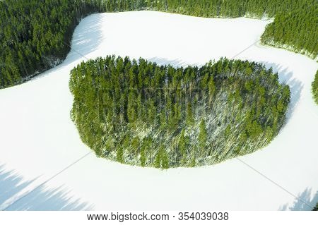 Aerial View Of Frozen Wild Forest Lake At Winter Time. Small Frozen Lake In Green Pine Tree Forest.