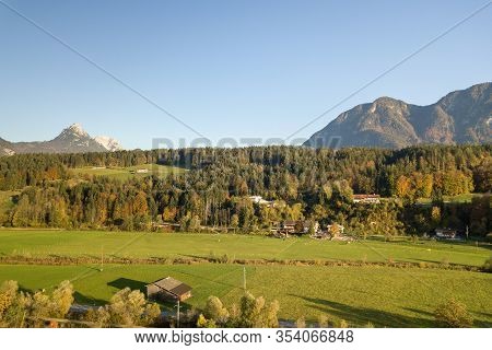 Aerial View Of Green Meadows With Villages And Forest In Austrian Alps Mountains.