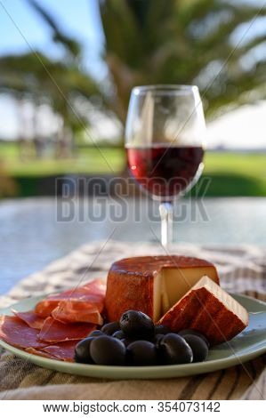 Tastes Of Spain, Jamon Iberian, Black Olives, Manchego Cheese With Red Paprika And Glass With Red Ri