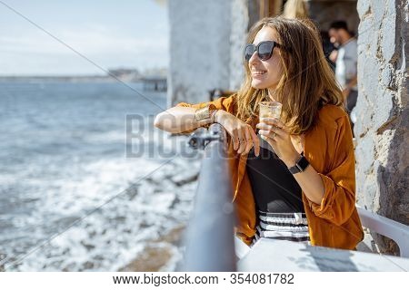 Young Woman Enjoying Ocean Views During A Summer Time, Sitting With Cortado Coffee At The Cafe Terra