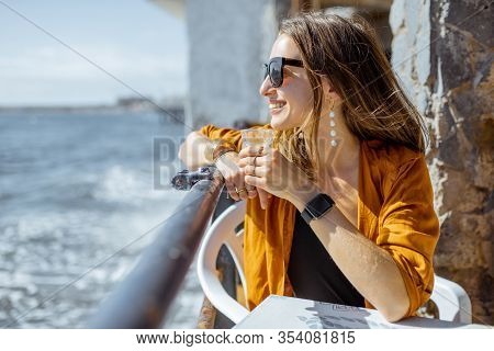 Young Woman Enjoying Ocean Views During A Summer Time, Sitting With Cortado Coffee At The Cafe Terra