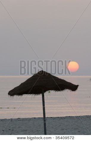 Solen stiger över en cafébar strand
