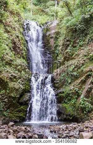 Powerful Waterfall In The Tropical Mountains Of Costa Rica Surrounded By Dense And Healthy Vegetatio