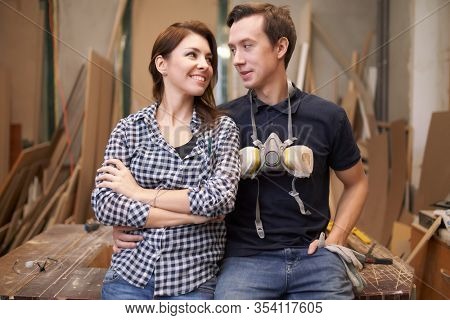 Loving couple joiners sitting in workshop.