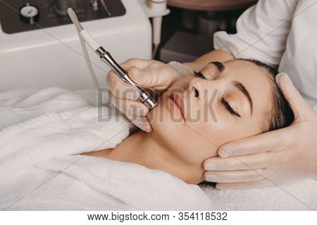 Brunette Caucasian Woman Having A Spa Procedure For The Skin Of Her Face Done With An Apparatus By A
