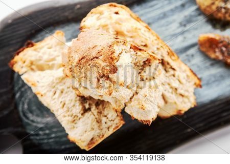 Burnt ciabatta with two kinds of butter. Aromatic fresh bread on wooden cutting board. Delicious rustic meal and cooking utensil. Traditional italian dish. Food presentation, pastry on white surface
