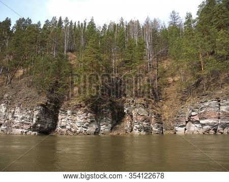 A Calm River Flowing Among Beautiful Unusual Mountains Which Include Pine Trees, Rocks, Natural Land