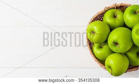 Apples Harvest Concept. Braided Bamboo Basket With Green Apples On White Wooden Background With Copy