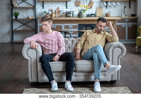 Two Men Sitting On The Sofa Not Loooking At Each Other Looking Upset
