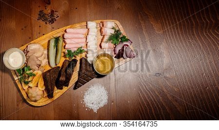 Sliced From Various Types Of Lard, Ham With Sauce And Pickles On A Wooden Board. Top View