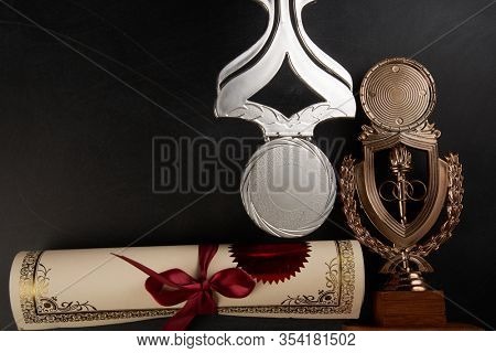 Golden trophy and certificate over blackboard background. top view. flat lay.Trophy is a specific achievement, serves as recognition / evidence of merit, awarded for sporting events