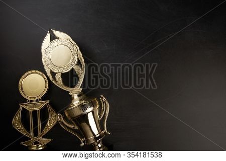 Golden trophy over blackboard background. top view. flat lay.Trophy is a specific achievement, serves as recognition / evidence of merit, awarded for sporting events