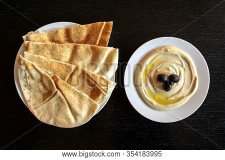 Famous traditional Arabic, Middle East, Israel cuisine. Tahina dipping, pita bread and falafel on dark wooden table background. Flat lay, top view. Egipt food.