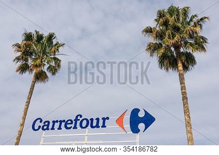Finestrat, Spain - March 5, 2020: Carrefour Logo On Carrefour Supermarket With Blue Sky And Palms Ba