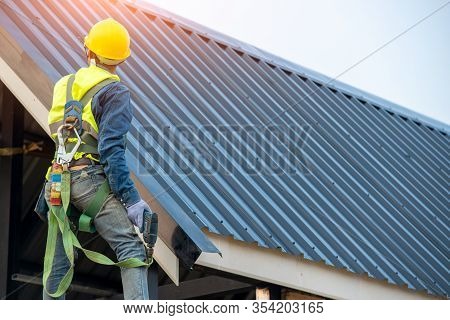 Roofer Worker In Protective Uniform Wear And Gloves, Using Air Or Pneumatic Nail Gun And Installing 