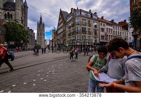 Ghent, Belgium, August 2019. Two Boys With Their Mother Consult The Tourist Map, Behind Them Are The