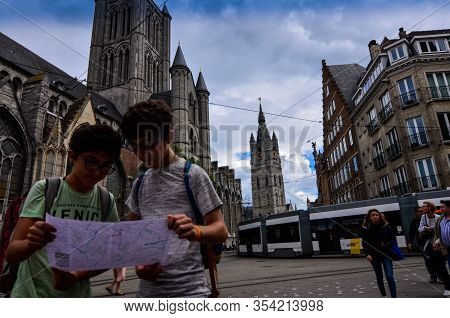 Ghent, Belgium, August 2019. Two Boys Consult The Tourist Map, Behind Them We Recognize The Church O