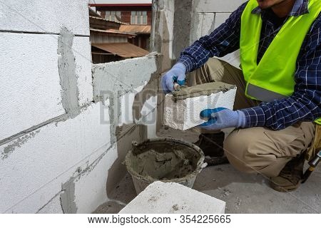 Bricklayer Builder Working With Autoclaved Aerated Concrete Blocks. Walling, Installing Bricks On Co