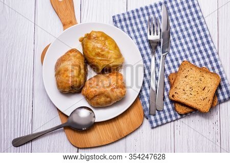 Cabbage Rolls With Meat, Rice And Vegetables In A White Plate On A Wooden Table. Stuffed Cabbage Lea