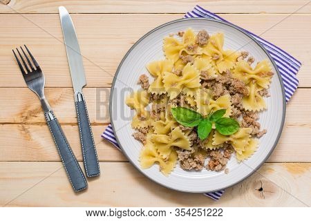 Ready-to-eat Pasta Navy With Minced Meat And Basil Leaves On A Plate And Cutlery On A Wooden Table. 