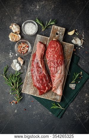 Raw Fresh Steak Sirloin Flap Served With Rosemary, Garlic And On Wooden Cutting Board. Black Angus B