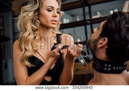 Selective Focus Of Sexy Dominant Woman Pulling By Bdsm Leash On Submissive Boyfriend On Bed