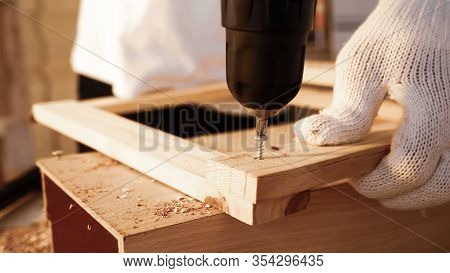 Close Up Of Carpenter Using Drill To Screwing Pieces Of Board At Site.