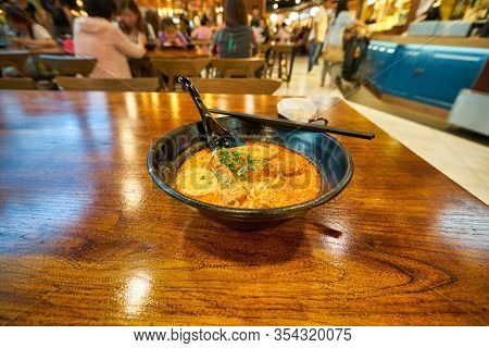SINGAPORE - JANUARY 20, 2020: Laksa served on a table in the Shoppes at Marina Bay Sands. Laksa is a spicy noodle soup popular in the Peranakan cuisine of Southeast Asia