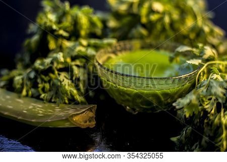 Anti-aging Face Mask On The Black Colored Glossy Surface Consisting Of Fresh Green Cilantro Leaves,
