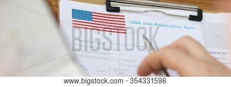 Close-up Of Clipboard With Usa Visa Application Form On First Page. Persons Hand With Pen To Fill Sp