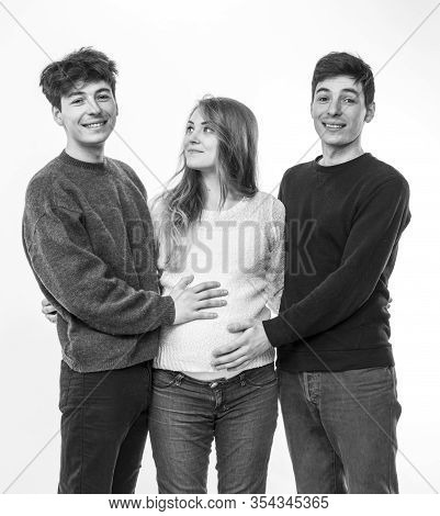 Young Pregnant Woman Posing With Two Young Man On A White Background