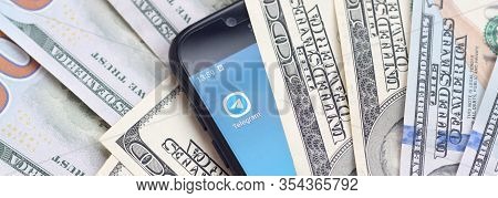 Smartphone Screen With Telegram App And Lot Of Hundred Dollar Bills. Business And Social Networking 