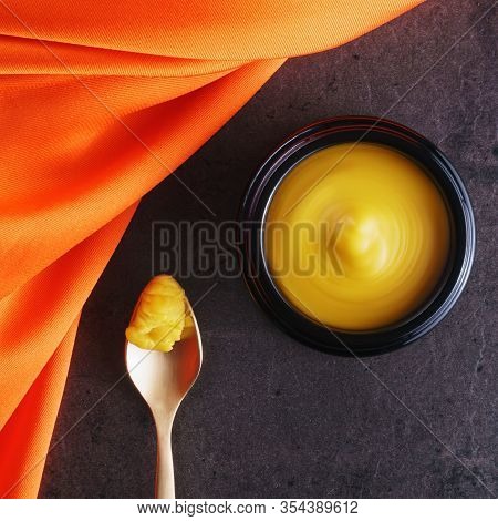 Beautiful Picture Of Golden Solid Skincare Oil In Elegant Black Glass Jar And Golden Spoon Accentuat