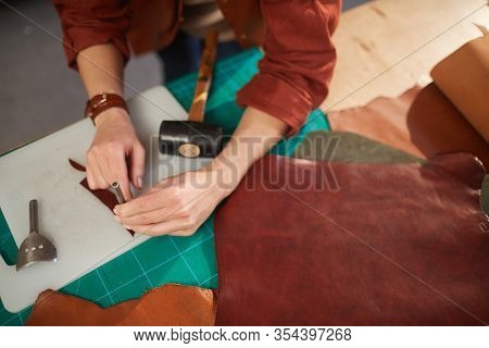 Horizontal From Above Shot Of Unrecognizable Female Artisan Using Leater Punching Tool On Small Deta