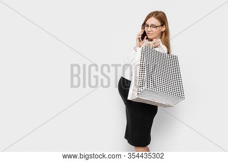 Image Of Young Pregnant Businesswoman Wearing Glasses, Talking On Phone, Holding Bags, Shopping