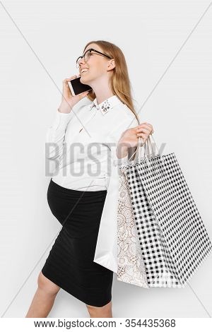 Image Of Young Pregnant Businesswoman Wearing Glasses, Talking On Phone, Holding Bags, Shopping