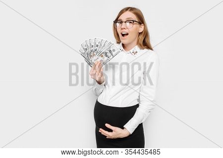 Image Of A Young Pregnant Businesswoman In Glasses Posing, Holding Banknotes In Her Hands, Planning